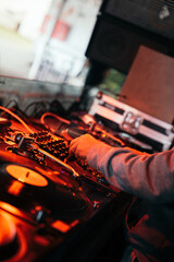 DJ ajustando el mixer junto a un disco de vinilo girando en un tocadiscos en un club con luz roja