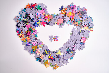 Many puzzle pieces in the shape of a heart. Background image of scattered colorful puzzle pieces
