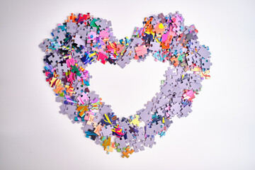 Many puzzle pieces in the shape of a heart. Background image of scattered colorful puzzle pieces