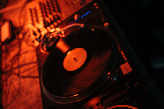Vinilo girando en un tocadiscos bajo la luz roja de un club