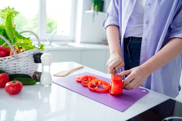 Obraz na płótnie Canvas Cropped photo of lady dressed purple shirt cooking supper cutting sweet red pepper indoors house kitchen