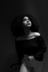 Black and white portrait of young woman with black power hair looking up.