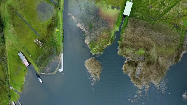 Aerial view of a lagoon (La Cocha, Colombia), part of the dock, its wetland, and houses surrounding the lagoon.