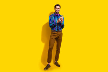 Full size photo of intelligent guy dressed striped shirt trousers hold smartphone read notification isolated on yellow color background