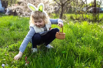  Little girl gathering colorful egg in park. Easter hunt concept © Maryna