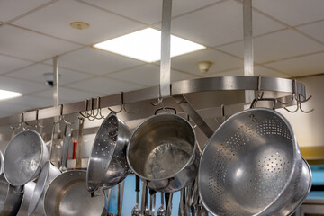 Stainless steel pots and pans and other cooking utensils hanging in a commercial industrial...