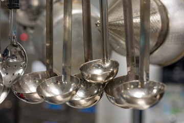 Stainless steel cooking utensils hanging in a commercial industrial kitchen. 