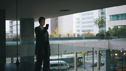 Thoughtful businesswoman looking smartphone on dark balcony. Nervous woman walk