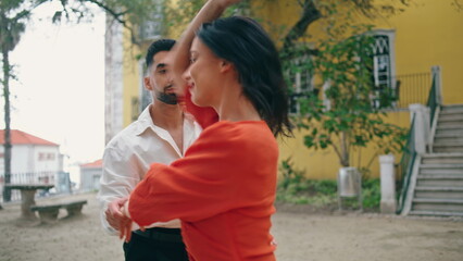 Energetic couple enjoy latino dance on city street closeup. Artists dancing park
