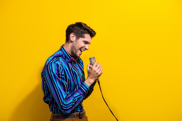Portrait of positive nice guy dressed stylish shirt bow tie singing in microphone in hands isolated...