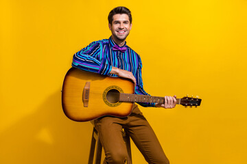 Portrait of positive cheerful nice man with bristle wear vintage bow tie sit on stool hold guitar...