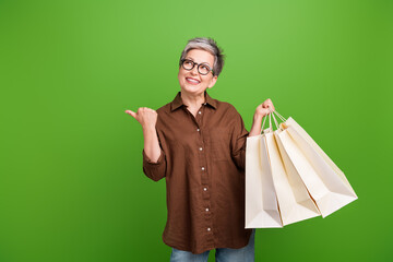 Portrait of pleasant person with gray hairstyle in glasses hold new outfit look directing empty...