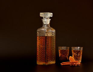 Fig liqueur with cinnamon and anise, homemade alcohol with spices in a crystal decanter and two...