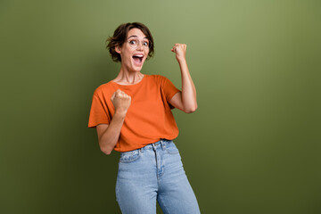 Fototapeta na wymiar Photo of young funny woman raised fists up celebrate her business startup received government grant isolated on khaki color background