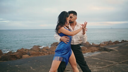 Passionate latino dancers enjoy hot performance on cloudy pier. Couple dancing