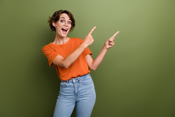 Portrait of astonished crazy person wear stylish t-shirt in eyewear directing at billboard empty space isolated on green color background