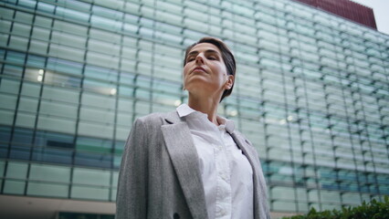 Successful businesswoman admiring office buildings. Pensive woman executive rest