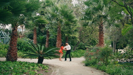 Energetic professional dancers performing latino style in tropical garden. 