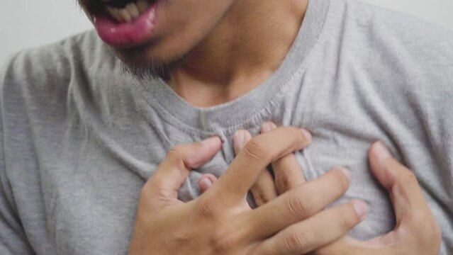 Young man with heart disease, holding hands on chest. Heart attack or stroke. risk of coronary heart disease, diabetes, hyperlipidemia, high blood pressure. isolated.