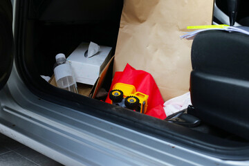 In the car full of belongings, plastic bags, plastic water bottles, document files, paper bags,...