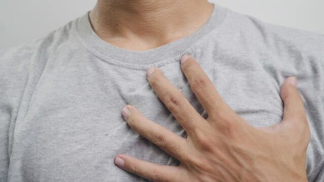 Young man with heart disease, holding hands on chest. Heart attack or stroke. risk of coronary heart disease, diabetes, hyperlipidemia, high blood pressure. isolated.