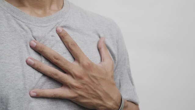 Young man with heart disease, holding hands on chest. Heart attack or stroke. risk of coronary heart disease, diabetes, hyperlipidemia, high blood pressure. isolated.
