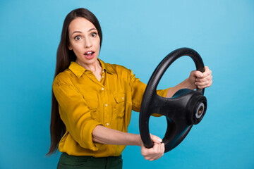 Photo of impressed funky lady wear yellow shirt riding auto steering wheel isolated blue color...