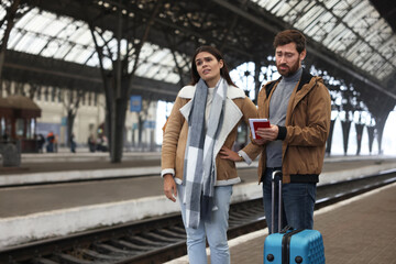 Being late. Worried couple with suitcase waiting at train station, space for text