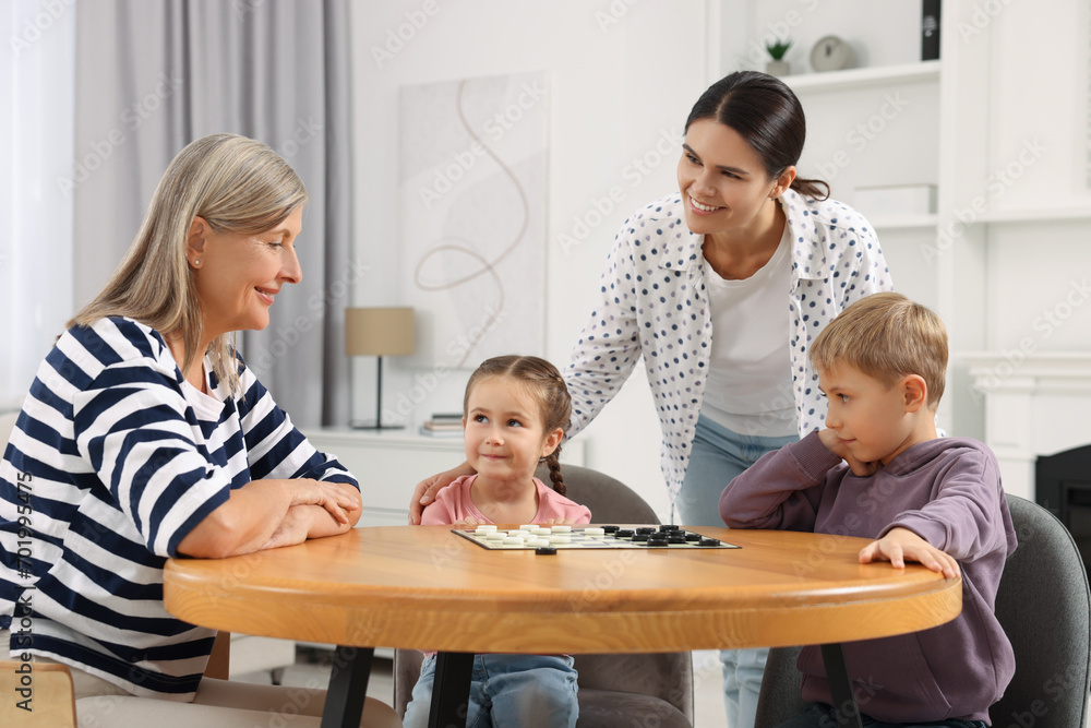 Canvas Prints Family playing checkers at wooden table in room