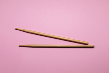 Two wooden drum sticks on pink background, top view