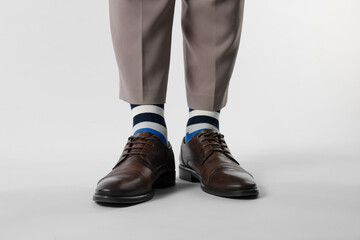 Man in stylish colorful socks, shoes and pants on white background, closeup
