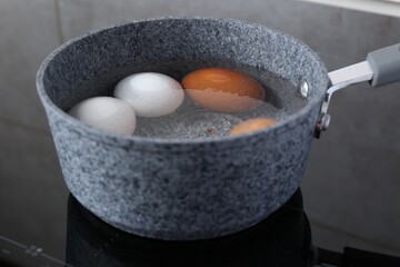 Chicken eggs boiling in saucepan on electric stove, closeup
