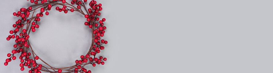 Banner of colorful background with strips of red berry garland on grey. Festive Christmas birthday...
