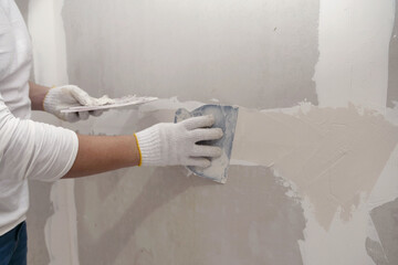 Plasterwork and wall painting preparation. Asian male applying filling drywall patch. - obrazy, fototapety, plakaty