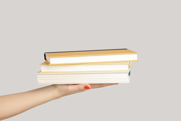 Closeup of woman hand showing lots textbooks or organizers, education, reading literature. Indoor studio shot isolated on gray background.