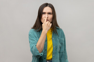 You are liar. Portrait of serious young woman with dark standing with finger on her nose and...