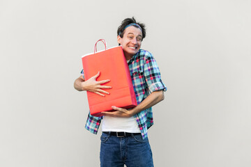 The best gift ever. Handsome man standing, hugging his lovely red shopping bag or gift and...