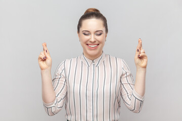 Portrait of smiling cheerful attractive beautiful woman wearing striped shirt crossing her fingers,...