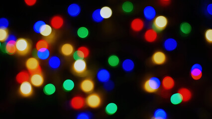 Defocused blurry multicolored blinker lights bokeh of Christmas and New year decoration lights, abstract, dark background, overlay for party, shallow DOF, festive mood