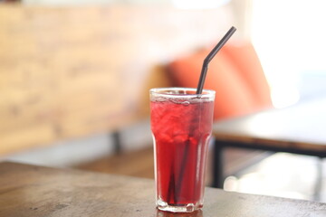 Iced Hibiscus tea in glass on wooden table in coffee shop.