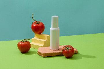 Cosmetic bottle in white color decorated with few tomatoes. Skin care concept with empty label. Tomato benefits the skin in a number of different ways