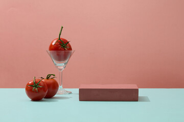 A cocktail glass containing a tomato, placed next to a rectangle podium. Concept scene stage...