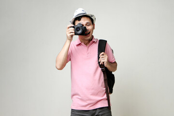 Asian man backpacker taking photo with digital camera. travelling concept. on isolated background