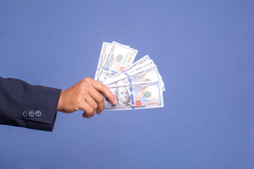 Hand holding money dollar bills isolated over blue background