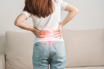 woman having back body ache during sitting on Couch at home. adult female with muscle pain due to...