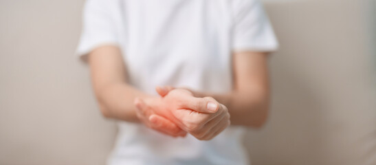Woman having wrist pain during sitting on sofa at home, muscle ache due to De Quervain s tenosynovitis, ergonomic, Carpal Tunnel Syndrome or Office syndrome concept - obrazy, fototapety, plakaty