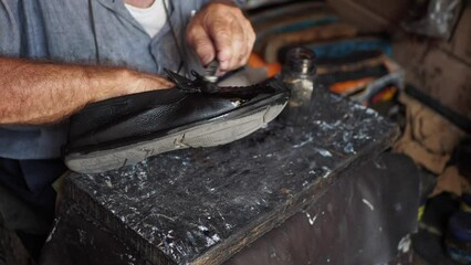  A cobbler's hands mending shoe stitching with needle 