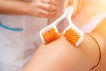 The masseur makes anti-cellulite massage using a roller massager. Physiotherapy and rehabilitation...