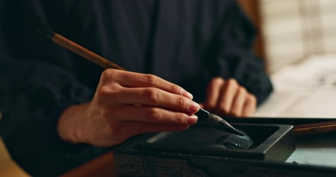 Hands, reed pen or brush in ink for writing, calligraphy or ancient script for art and inkstone. Japanese creativity, black paint and vintage tools, paintbrush and stroke, traditional and stationery