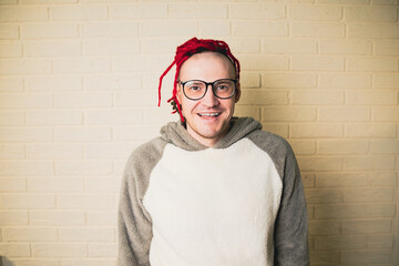 young attractive hipster man with red dreadlocks in glasses and a white sweater on the background...